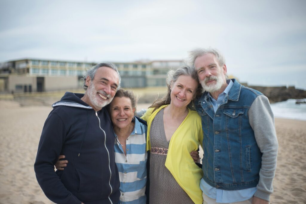 Two couples on a beach looking happy.